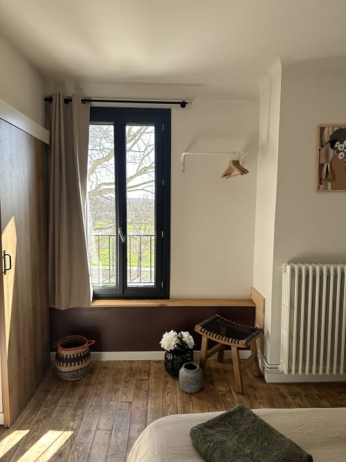 Cozy bedroom nook at Le Mas de la Vernède with black French doors, wooden floor, and rustic decor