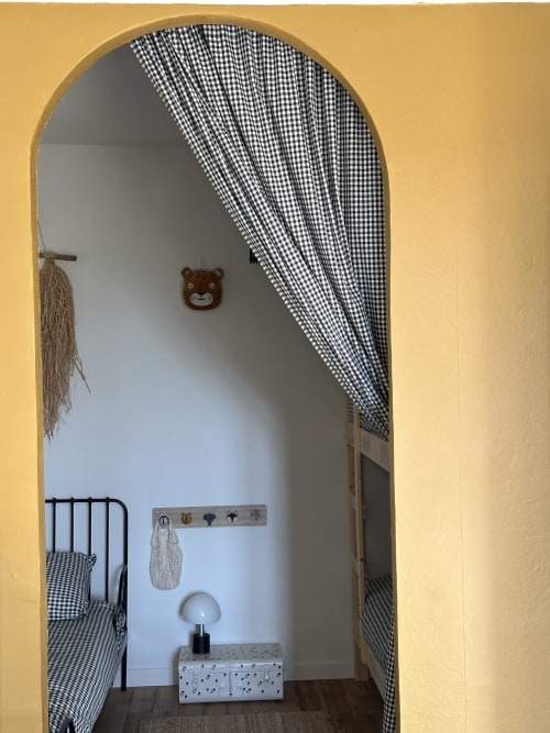 L'Écrin room at Le Mas de la Vernède in Aramon with gingham curtains, bear decoration, and iron bed