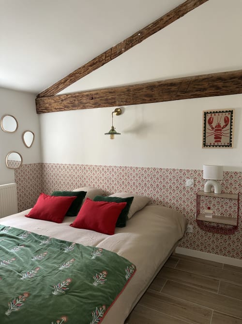 Chambre chaleureuse au Mas de la Vernède avec poutres apparentes, tête de lit à motifs, oreillers rouges et homard