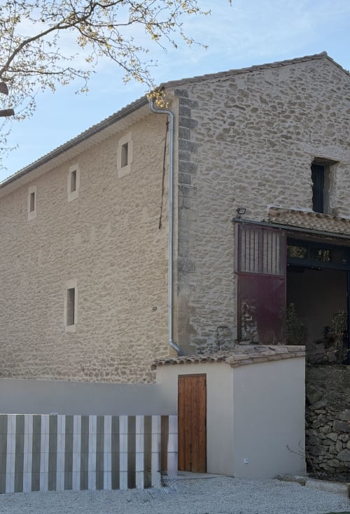 Le Mas de la Vernède stone building exterior in Aramon with rustic wooden door and modern entrance