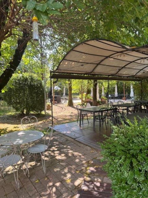 Area esterna per cena dell'Agriturismo Aggazzotti con pergolato, tavoli e rigogliosa vegetazione in Italia