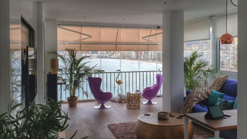 Salón moderno de apartamento en Benidorm con sillas púrpuras, vistas al mar, plantas y horizonte de ciudad costera