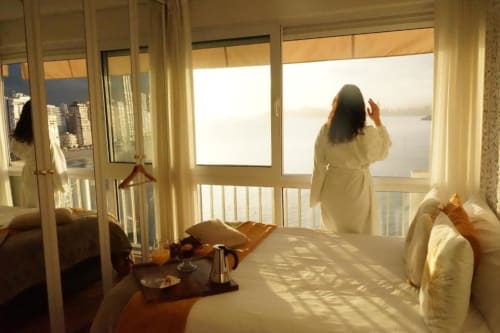 Mujer disfrutando del atardecer desde el balcón de Portofino Playa con vistas a la playa de Benidorm y el mar Mediterráneo