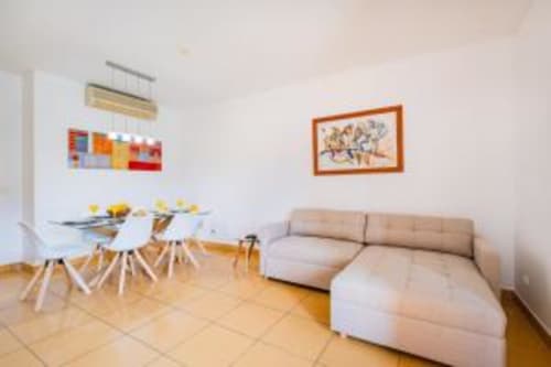Sala de estar do Marina Prestige com sofá bege, mesa de jantar e vista para o jardim em Albufeira