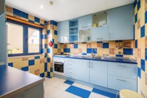Cozinha moderna com azulejos xadrez azul e amarelo, móveis brancos e eletrodomésticos contemporâneos na Atlantic Places