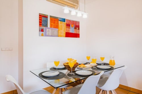 Moderna área de refeições no Apartamento Marina Prestige em Atlantic Places Albufeira com mesa posta e arte abstrata colorida na parede