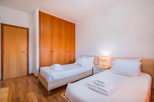 Quarto twin no Apartamento Marina Prestige, Atlantic Places, Albufeira com guarda-roupa em madeira e vista para o jardim