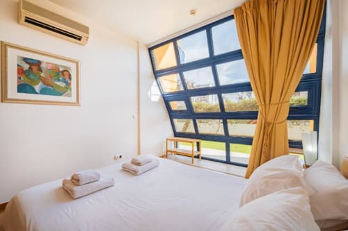 Quarto moderno no Marina Prestige Apartment em Albufeira com vista para o jardim, janelas com moldura azul e cortinas douradas