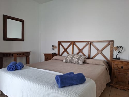 Bedroom with two beds and wooden furniture in Villa 7 at Villas del Mar, Puerto Calero