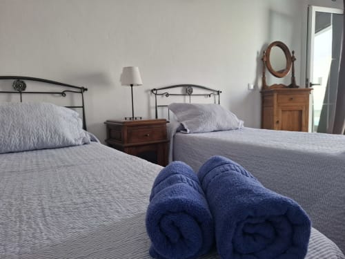 Twin beds with rolled towels at Villas del Mar, Puerto Calero. Bedroom with metal headboards and wooden furniture.