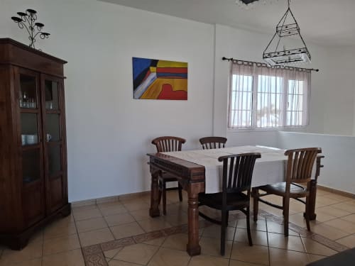 Dining area in Villa 7 at Villas del Mar, Puerto Calero with wooden table, chairs, and sea view windows