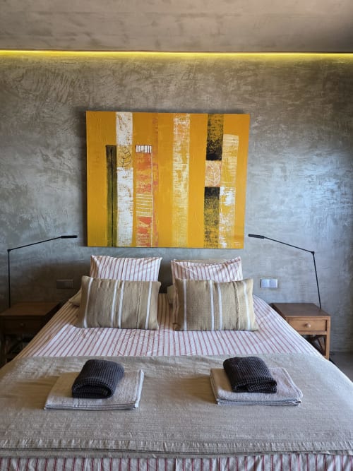 Quarto moderno em Les Terrasses Les Suites com obra de arte com listras amarelas, roupa de cama listrada e paredes texturizadas cinzentas em Calheta