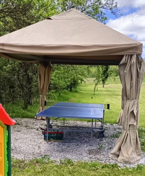 Table de ping-pong sous gazébo beige avec vue sur la campagne au Domaine de la Méouge