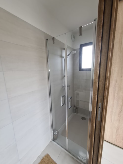 Modern shower with a glass partition and rainfall showerhead in the Villa Corsica bathroom in Favone, managed by the Corsu di Core concierge service.