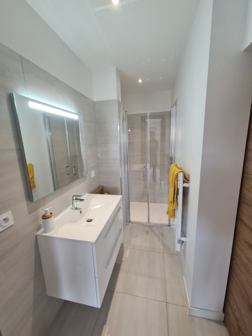Contemporary bathroom at Villa Corsica, featuring a white basin, a backlit mirror and a glass walk‑in shower, managed by the Corsu di Core concierge service.