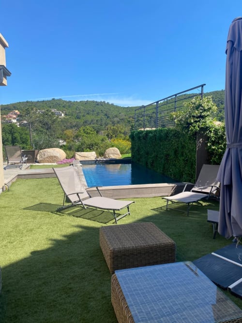 Luxury villa pool area with lounge chairs, manicured lawn, and forested hillside views in Favone - managed by Corsu Di Core