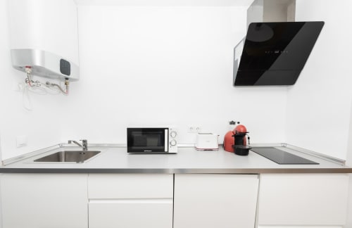 Modern white kitchen counter at Sur Suites Málaga with sink, microwave, and appliances