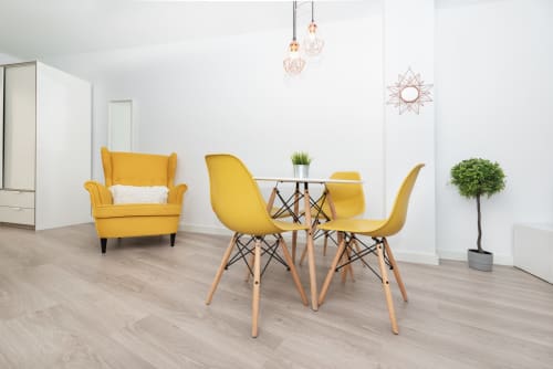 Bright yellow modern loft at Sur Suites Málaga with dining table, chairs, armchair, and potted plant