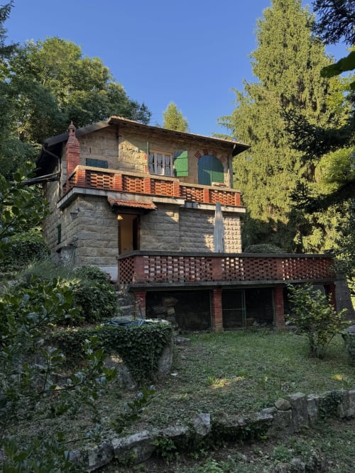 Villa Vittoria a Sanremo circondata da lussureggianti alberi e giardini, con balconate in mattoni e architettura in pietra.