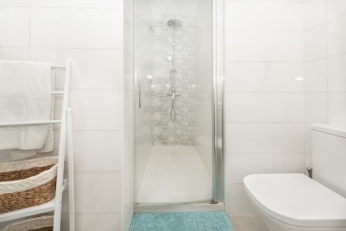 Modern bathroom at Sur Suites Málaga with walk-in shower, white subway tiles, and turquoise floor mat
