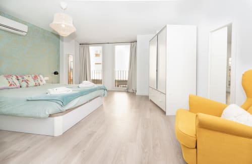 Sur Suites Málaga Fantástico Loft Amarillo: bright bedroom with yellow armchair, turquoise accents, and balcony access