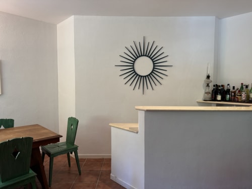 Elegante sala da pranzo in villa moderna con orologio a raggi solari, sedie verdi, tavolo in legno e bancone bar a Sanremo
