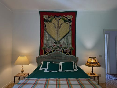 Camera elegante a Villa Vittoria a Sanremo con biancheria verde, testata ornata in rosso e lampade da comodino