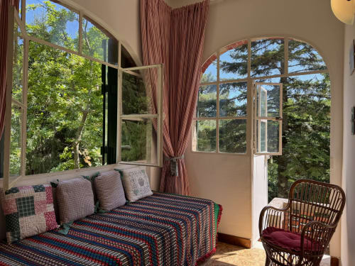 Camera luminosa e soleggiata a Villa Vittoria, Sanremo con vista sul giardino, daybed, finestre ad arco e vegetazione rigogliosa