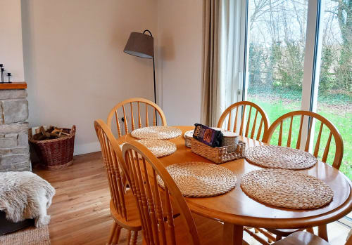 Leitrim Quay cottage dining area with wooden table, woven chair cushions, and garden views