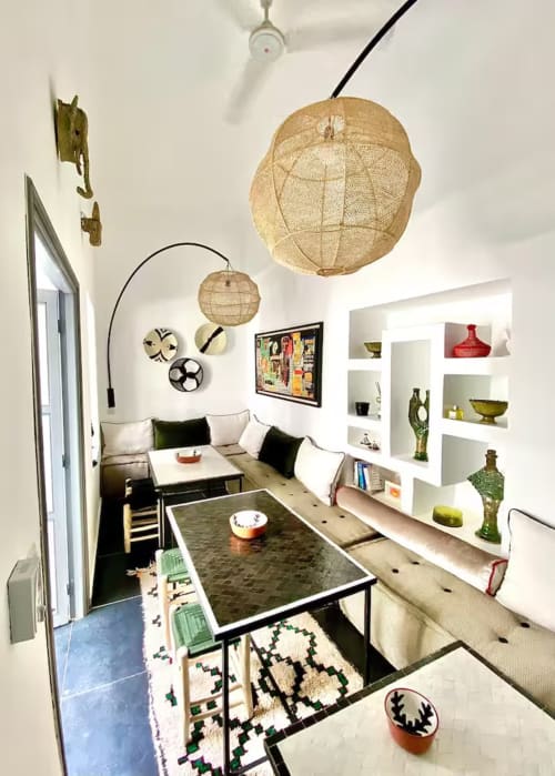 Salon moderne dans un riad de Marrakech avec luminaires suspendus tissés, étagères intégrées et mobilier contemporain