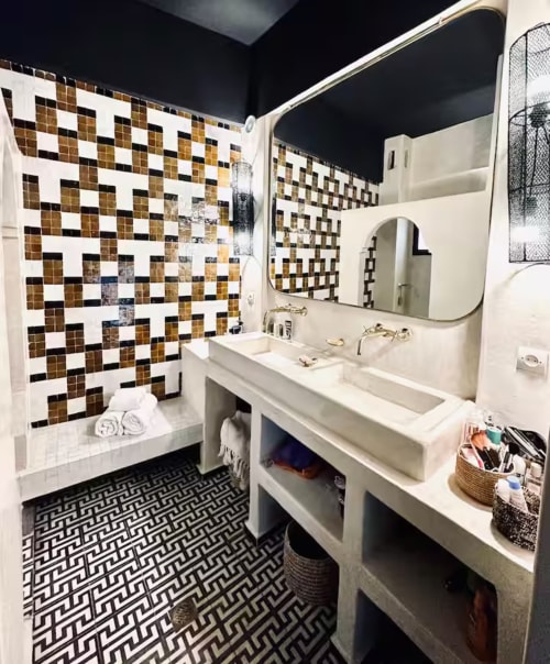 Salle de bain moderne du Riad 191 Marrakech avec douche aux carreaux géométriques, meuble vasque blanc et sol à motifs