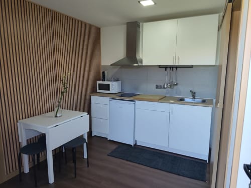 Cozinha moderna com armários brancos, mesa de jantar e parede em madeira - Quinta Salinas Bungalow Deluxe, Aveiro