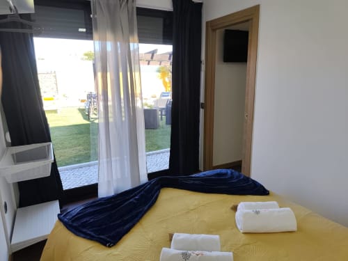 Quarto Bungalow Deluxe com roupa de cama amarela, manta azul, toalhas brancas e portas para o jardim na Quinta Salinas