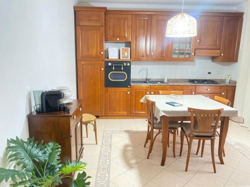 Ampia zona cucina-sala da pranzo nell'appartamento Iris di Le case di Clara con mobili in legno, tavolo da pranzo e elettrodomestici moderni