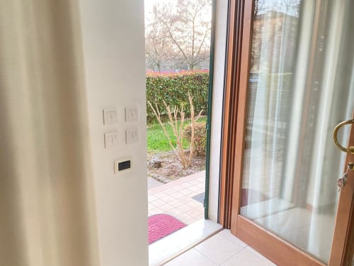 Vista del giardino dall'appartamento Iris di Le case di Clara, con porte-finestre, siepi e alberi spogli