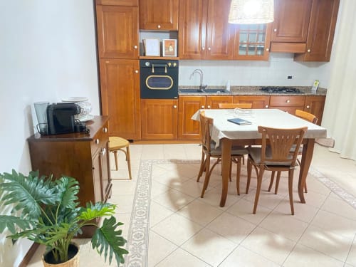 Ampia zona cucina-pranzo dell'appartamento Iris presso Le case di Clara con mobili in legno, tavolo da pranzo e pianta in vaso