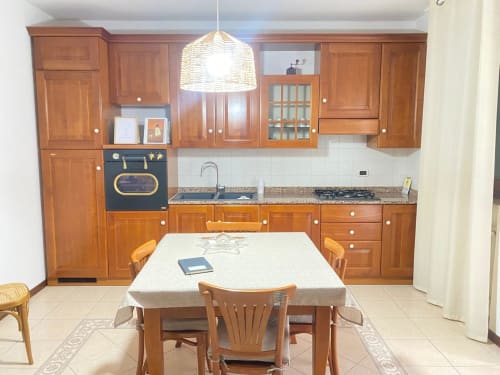 Ampia zona cucina-pranzo dell'appartamento Iris presso Le case di Clara con mobili in legno, tavolo da pranzo e elettrodomestici moderni