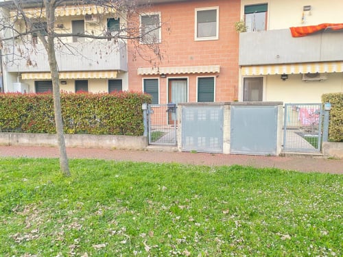 Esterno del garden apartment Le case di Clara con edificio in mattoni, prato verde, siepi e cancelli in ferro in Italia