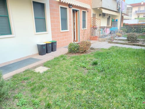 Appartamento Le case di Clara con vista sul giardino Iris: casa in mattoni, prato verde, patio in mattoni e contenitori rifiuti