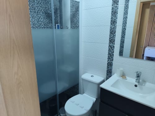 Casa de banho moderna no Bungalow Deluxe Quinta Salinas, Aveiro, com chuveiro de vidro fosco, lavatório branco, sanita e