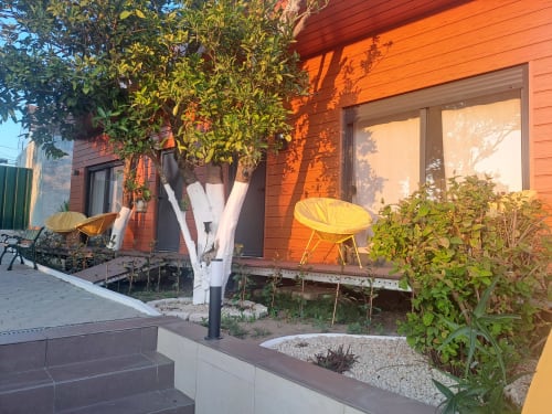 Pátio do Bungalow Veneza na Quinta Salinas, Aveiro com fachada laranja, cadeiras amarelas, jardim e comodidades modernas