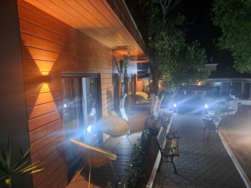 Pátio do bungalow Quinta Salinas à noite com iluminação acolhedora, fachada de madeira, assentos no pátio e caminho de jardim em Aveiro
