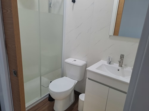 Banheiro moderno da Bungalow Veneza no hotel Quinta Salinas, Aveiro, com vaso sanitário, pia e box de vidro para duche