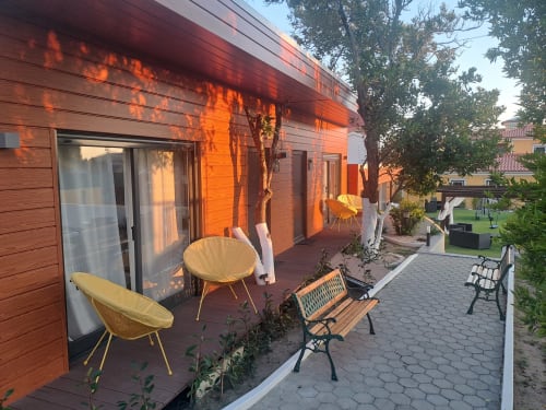 Bungalow Santiago na Quinta Salinas com varanda de madeira, cadeiras amarelas modernas e vistas de jardim em Aveiro