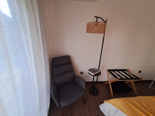 Bungalow Santiago na Quinta Salinas com poltrona preta, luminária de arco em vime, mala de madeira e piso em madeira em Aveiro
