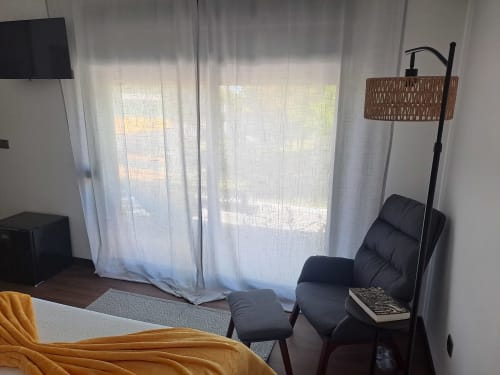 Bungalow Santiago no hotel Quinta Salinas em Aveiro com apartamento moderno, vista para o jardim, poltrona preta, TV e cortinado