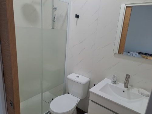Banheiro moderno do Bungalow Santiago no hotel Quinta Salinas, Aveiro, com sanitário, lavatório e chuveiro em vidro