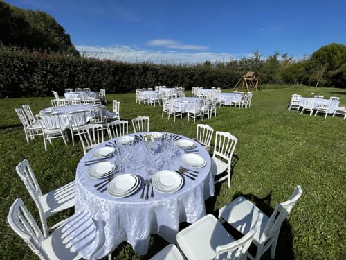 Réception de mariage en plein air aux Jardins Du Soleil à Avignon avec tables rondes, chaises blanches et jardins paysagers.