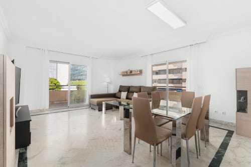 Spacious modern apartment living room in Marbella with dining area, terrace access, and city views