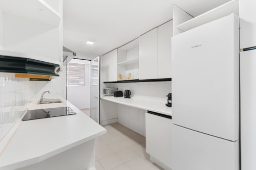 Modern kitchen with white cabinetry, Bosch refrigerator, and black accents in Marbella apartment rental